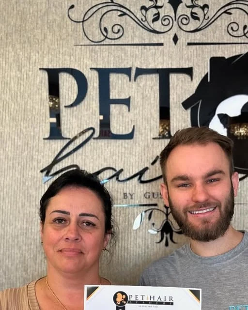 Aluna segurando o certificado ao lado de Gustavo Zilli, em frente ao letreiro do Pet Hair